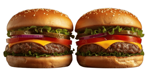 Two cheeseburgers side by side on a solid teal background, each with a sesame seed bun, beef patty, melted cheese, tomato slices, red onion, pickles, and leafy lettuce.